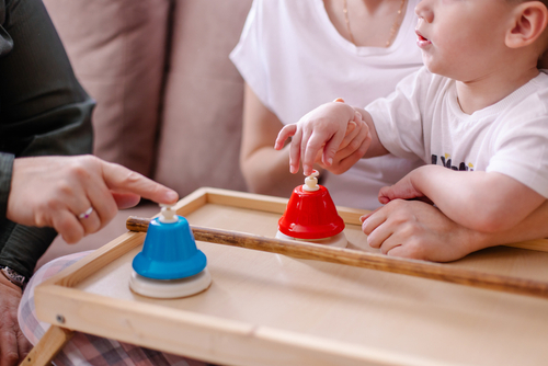 A mother is engaged in a music lesson with her child with cerebral palsy. Rehabilitation with musical instruments. Hands with hypertonicity with bells close-up. Disability