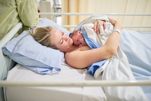 Hospital, motherhood and woman with newborn, happy and love for baby on bed, labor or healthy. Clinic, hug and temperature regulation with skin contact, healthcare or new parent with care for infant